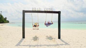 Caucasian couple in love enjoy swings have fun together on summer beach holidays express emotions being childish silly relaxed outdoors together. Cheerful carefree traveling couple video