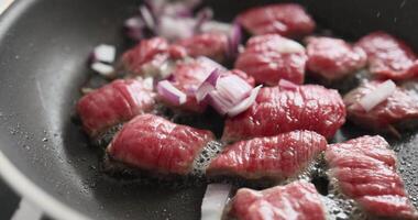 Juicy Australian beef is frying in a pan with oil. The chef is sprinkling fresh video