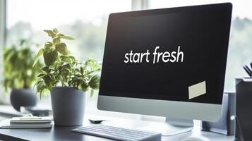 Inspirational workspace with computer monitor displaying Start fresh in bright office setting. Symbolism of fresh starts photo