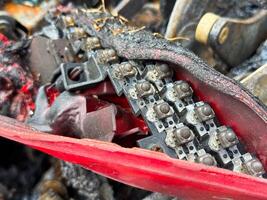Close-up of a melted LED circuit board inside a burned car tail light assembly, showing damaged electronic components and charred red plastic housing after fire photo