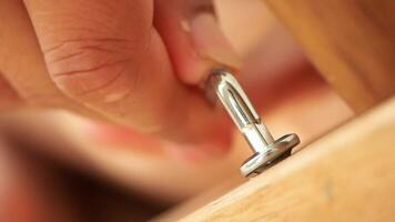 Installing a metal hook into a wooden surface for secure hanging video