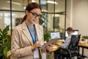 Engaging professional woman using tablet in modern office filled with greenery photo