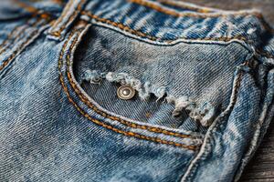Close-up view reveals history of wear on an old blue denim pocket showing frayed edges and faded stitches over time photo