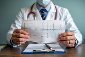 Doctor examines heart rhythm chart in modern medical office during routine patient checkup photo