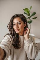 Young woman enjoying a cozy moment at home while taking a self-portrait with a warm smile in her comfortable sweater photo