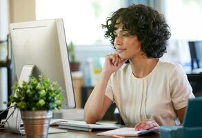 Focused professional woman in a warm office environment working deeply at her computer desk photo