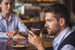 Young man enjoys a moment of peace with coffee and cookies at a busy bar in the afternoon photo