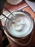 two hand mixer whisks in the process of whipping fresh white cream in a mixing bowl photo