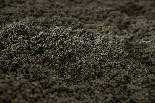 Detailed view of a rugged surface composed of small, dark granules with uniform size and color, highlighting the texture and uneven appearance. photo