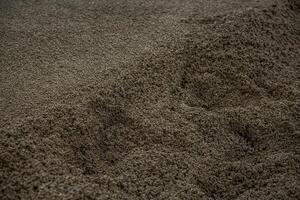 A detailed view of dark gray granular material with uneven ridges and depressions, highlighting the texture and natural patterns of the surface. photo