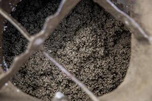 A detailed view of small metallic particles in a container, partially covered by a crisscross metal grate, highlighting texture and industrial design. photo