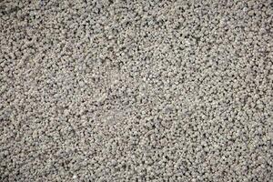 Close up view of a textured surface with small, uniform gray granules, possibly used in construction or underfloor heating applications. photo