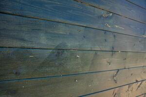 A detailed view of a wooden wall featuring horizontal planks with a dark, weathered finish. The surface shows grain patterns, knots, and subtle imperfections. photo
