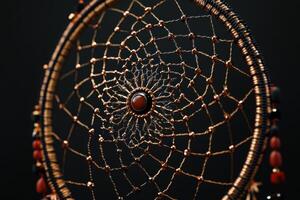 A gold and black dreamcatcher with a red stone in the center photo