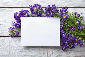Bright purple flowers surround a blank white card for mockup on a rustic wooden table, creating a serene and inviting atmosphere perfect for wedding invitations photo