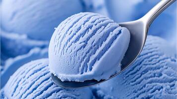 Blue ice cream scoop on a spoon against a backdrop of creamy ice cream in the bowl, showcasing the deliciousness and texture of the dessert while inviting indulgence photo