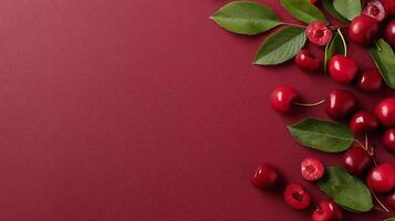 Fresh cherries scattered on deep red background with vibrant green leaves creating a lively and appealing arrangement photo