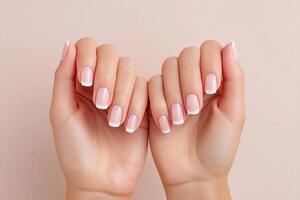 Elegant French manicure with natural nails displayed against a soft pink background in a serene atmosphere photo