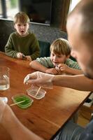Close-up of kids amazed faces as bubbling flask reacts. Father helps them explore science with joy. photo
