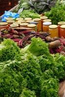 Fresh vegetables, fruits, and bottled preserves displayed on a rustic wooden stall, showcasing local farm products. photo