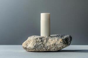 A white tube of lip balm sitting on top of a rock photo