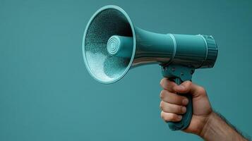 Hand holding a teal megaphone against a solid colored background in a bright and engaging setting photo