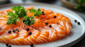 Fresh salmon sashimi served on a white plate with garnish of herbs and black pepper photo
