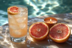 A glass of water with a grapefruit and a candle photo