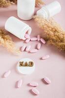 NAD molecule in pills for anti-aging and biohacking on pink background vertical view photo