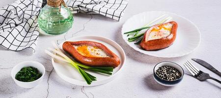 Fried egg in a sausage in the form of khachapuri on a plate on the table web banner photo