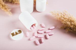 NAD molecule in pills for anti-aging and biohacking on pink background photo