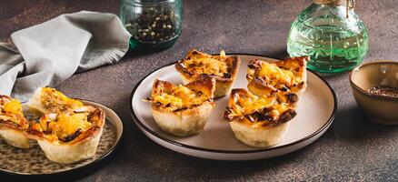 Mini tartlets with caramelized onions and cheese on a plate on a table web banner photo