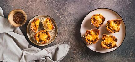 Homemade caramelized onion savory pies on a plate on the table top view web banner photo