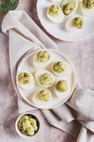 Avocado deviled eggs for appetizer on plate on table top and vertical view photo