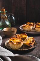 Mini tartlets with caramelized onions and cheese on a plate on a table vertical view photo