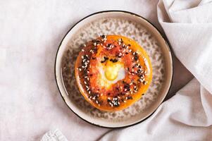Close up of baked bagel with tomato and quail egg on a plate on the table top view photo