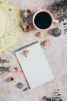 Notebook, beach hat, shells and stones on the table top and vertical view photo