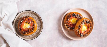 Egg with tomato and sesame seeds baked in bagels on a plate top view web banner photo