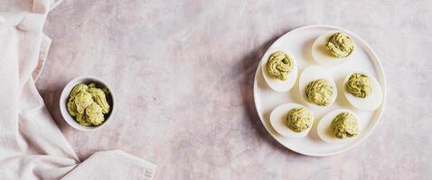 Avocado deviled eggs for appetizer on plate on table top view web banner photo