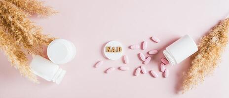NAD molecule in pills for anti-aging and biohacking on pink top view web banner photo
