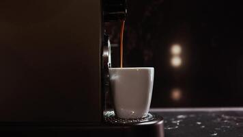 Making coffee into cup, espresso coming out from an automatic coffee maker machine. Beverage drink for breakfast in modern dark kitchen. Highlighting process of making aromatic espresso. Copy space video
