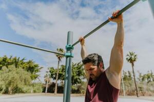 A man is holding a high bar at a calisthenics gym during a workout ready to do pull ups photo