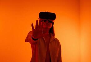 Front view of a woman immersed in VR world, Reaching forward with one hand, Interacting with Virtual Space, Virtual Space in a Sleek, Orange background photo