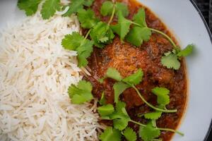 Delicious chicken curry served with fluffy basmati rice and garnished with fresh coriander leaves, creating a vibrant and aromatic culinary experience photo