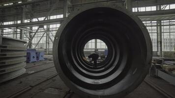An Industrial Worker is Seen Inside a Large Pipe Within a Busy Factory Setting Environment. Stock Clip photo