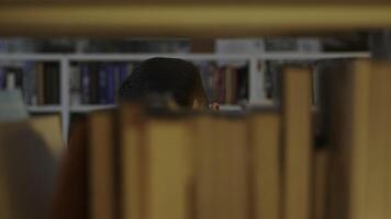 A Person Positioned Behind a Bookshelf Inside a Calm and Inviting Library Environment. Media photo
