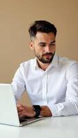 Professional man working on laptop in modern office setting, focused on task, dressed in white shirt, technology and productivity concept photo