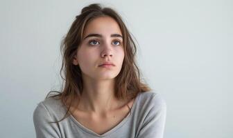 Thoughtful young woman gazing upwards with a pensive expression, reflecting on life and emotions, showcasing introspection and contemplation concept photo
