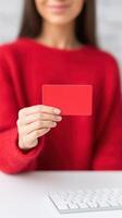 Woman holding a red card in front of a computer keyboard, showcasing a vibrant color contrast, modern workspace, creative concept, digital communication concept photo
