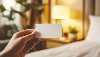 Hand holding blank business card in a hotel room, perfect for adding your own design or logo photo